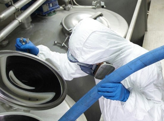 Technologie des tuyaux industriels Industrie alimentaire - utilisation du tuyau Goodall DuraCrimp Food (le tuyau bleu est alimenté dans un réservoir par un employé en tenue de protection)