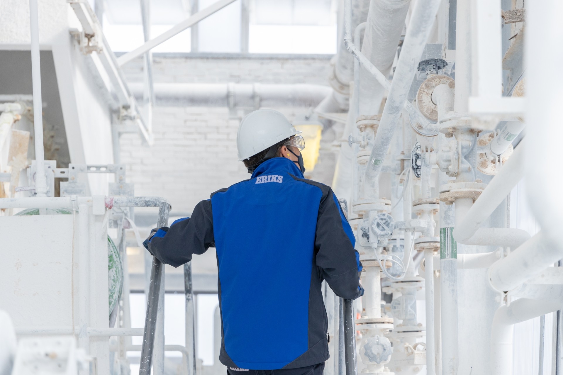 La sécurité dans l'industrie chimique Spécialiste ERIKS regardant les tuyaux et montant un escalier dans une usine chimique